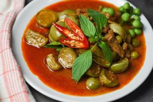 Thai food curry soup on white plate - red curry pork cuisine asian food on the table background photo