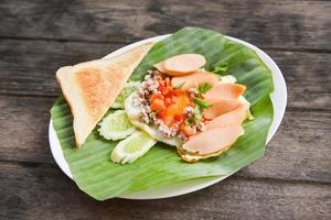 Fried eggs with sausage cucumber pork and bread for breakfast on banana leaf background - Pan Fried Egg with Toppings photo