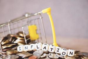 inflation with coin and shopping cart on wooden background, business economy inflation concept of money and finance - Rising grocery prices and surging cost more expensive things photo