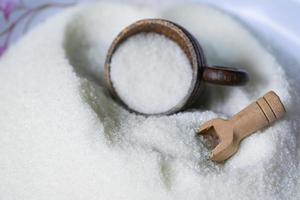 Sugar with cup and wooden scoop, white sugar for food and sweets dessert candy heap of sweet sugar crystalline granulated photo