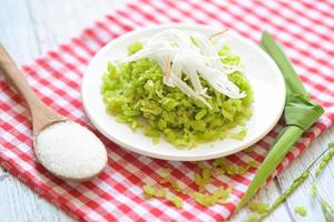 Green rice sweet with ears of rice pandan leaf, Thai dessert - pounded unripe rice food rice flakes cereal with coconut and sugar, Food dessert or snacks - Khao Mao name in Thailand photo