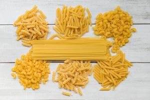 Raw pasta various kinds of uncooked pasta macaroni spaghetti and noodles on wooden, Italian food culinary concept, Collection of different raw pasta on cooking table for cooking food photo