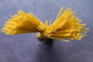 Raw spaghetti pasta uncooked, spaghetti noodles on dark background, raw pasta italian food photo