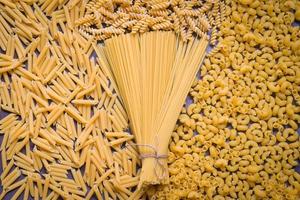 Raw pasta various kinds of uncooked pasta macaroni spaghetti and noodles on wooden, Italian food culinary concept, Collection of different raw pasta on cooking table for cooking food photo