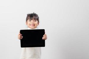 Asian little girl holding and using the digital tablet on white studio background, free copy space photo