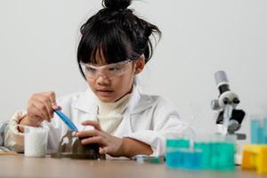 education, science, chemistry and children concept - kids or students with test tube making experiment at school laboratory photo