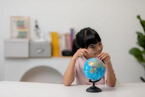 Asian little girl is learning the globe model, concept of save the world and learn through play activity for kid education at home. photo