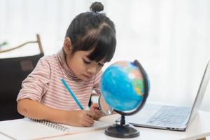 Asian little girl is learning the globe model, concept of save the world and learn through play activity for kid education at home. photo