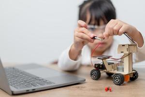 los estudiantes de asia aprenden en casa a codificar autos robot y cables de tableros electrónicos en tallo, vapor, ingeniería matemática, ciencia, tecnología, código de computadora en robótica para el concepto de niños. foto