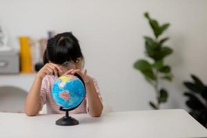 la niña asiática está aprendiendo el modelo del globo, el concepto de salvar el mundo y aprender a través de la actividad de juego para la educación de los niños en casa. foto