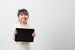 niña asiática sosteniendo y usando la tableta digital sobre fondo de estudio blanco, espacio de copia libre foto