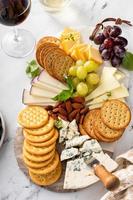 tabla de quesos con galletas, nueces y uvas foto