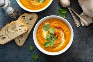 Pumpkin soup served with cream and cilantro photo