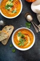 Pumpkin soup served with cream and cilantro photo