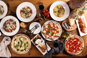 gran mesa con comida italiana, pizzas y pastas