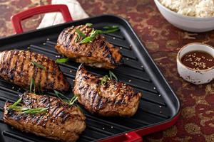 Grilled teriyaki chicken breast on a grill pan with green onions photo