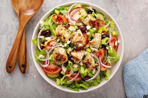 Greek salad with vinaigrette dressing topped with grilled chicken photo