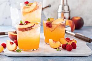 Refreshing summer cocktail with peach and raspberry photo