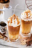 Iced pumpkin spice latte in tall glasses topped with whipped cream photo