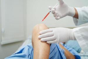 Asian doctor inject Hyaluronic acid platelet rich plasma into the knee of senior woman to walk without pain. photo