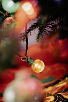 Yellow Christmas Light on a String of Lights Hanging in a Christmas Tree photo