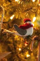 adorno navideño de pájaro colgado en un árbol de navidad con luces suaves foto