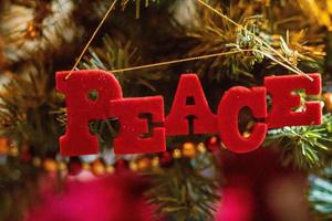 Adorno navideño de paz roja colgando de un árbol de Navidad foto