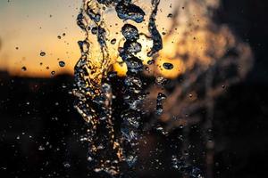 chorros de agua con muchas gotas y burbujas bajo el sol sobre un fondo amarillo anaranjado. un gran plan la textura de las ondas de agua de una gran fuente foto