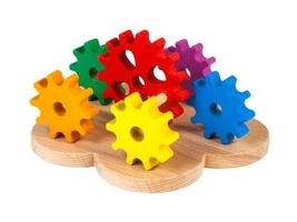 Photo of a wooden toy  children's sorter with small wooden details in the form of gears, in different colors  on a white isolated background. The toy for the development of fine motor child