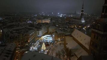 noche mágica de invierno sobre el casco antiguo de riga en letonia durante el tiempo de año nuevo. pequeño y acogedor mercado navideño con un increíble árbol de navidad en el centro de la ciudad. video