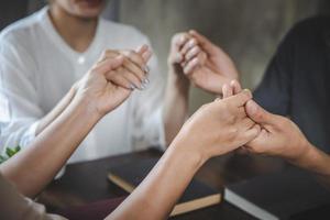 A group of Asian Christians sits inside a Catholic Church praying for God's blessing, the pale sun shining in the place of worship with copy space. photo