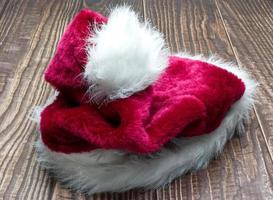 Red Santa Claus hat isolated on wooden background. photo