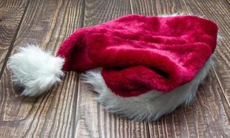 Red Santa Claus hat isolated on wooden background. photo