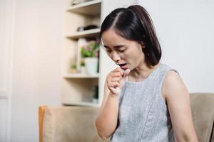 Sick woman coughing or wheezing sitting on a desk in the living room at home photo