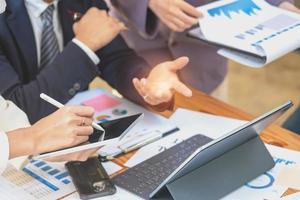 Asian business team consists of marketing staff. accountant and financial officer Help each other analyze company profits using tablets. calculator Laptop computers, graph paper, and corporate pens. photo