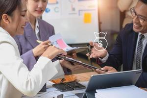 Asian business team consists of marketing staff. accountant and financial officer Help each other analyze company profits using tablets. calculator Laptop computers, graph paper, and corporate pens. photo