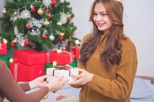 Merry Christmas and Happy Holidays Young woman with a beautiful face in a yellow shirt shows joy with gift boxes in a house with a Christmas tree decorated with Christmas tree.  Portrait before Xmas photo