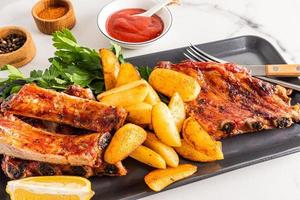 Front view of the dish with pork ribs and grilled potatoes. juicy delicious lunch or dinner. menu. photo