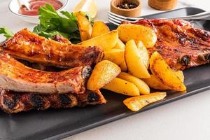 Front view of the dish with pork ribs and grilled potatoes. juicy delicious lunch or dinner. menu. photo