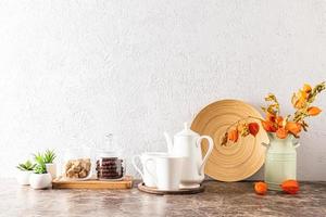 encimera de mármol de cocina con cafetera y tazas, latas de azúcar y café, jarra con flores secas en la pared con textura gris. un espacio de copia. foto