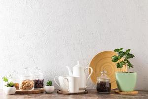 el fondo de la cocina de una encimera moderna. cafetera con tazas, tarros ecológicos de vidrio con azúcar de caña, granos de café, una olla con una planta de café.