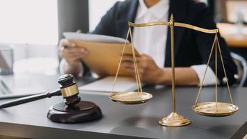 Justice and law concept.Male judge in a courtroom with the gavel, working with, computer and docking keyboard, eyeglasses, on table in morning light photo