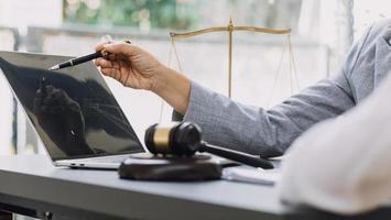 Business and lawyers discussing contract papers with brass scale on desk in office. Law, legal services, advice, justice and law concept picture with film grain effect photo