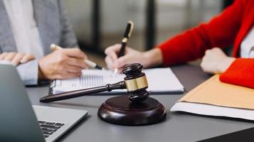 Justice and law concept.Male judge in a courtroom with the gavel, working with, computer and docking keyboard, eyeglasses, on table in morning light photo