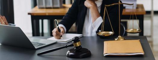 law books and scales of justice on desk in library of law firm. jurisprudence legal education concept. photo