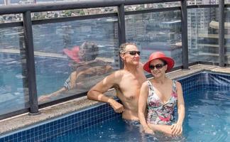 pareja en una piscina en la azotea disfrutando del día y la vista foto