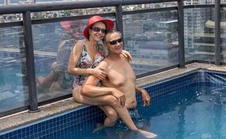 pareja en una piscina en la azotea disfrutando del día y la vista foto