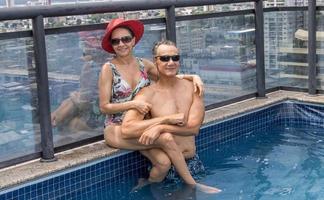 pareja en una piscina en la azotea disfrutando del día y la vista foto