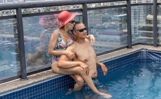 pareja en una piscina en la azotea disfrutando del día y la vista foto