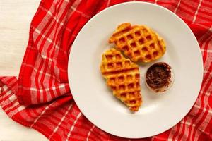 gofre croissant o croffle con salsa de chocolate servido en caja y fondo blanco foto